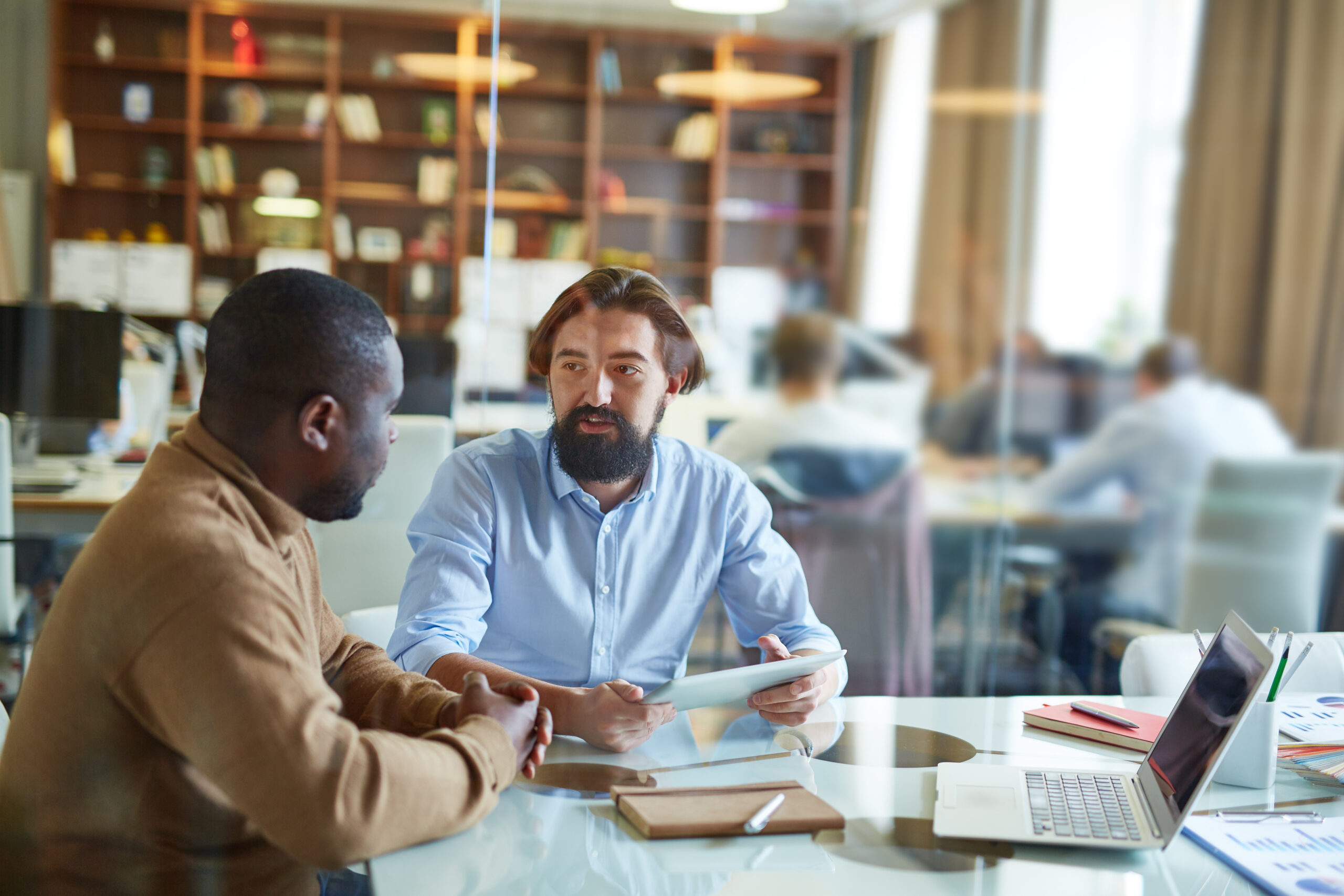 Two office workers discussing plans by desk